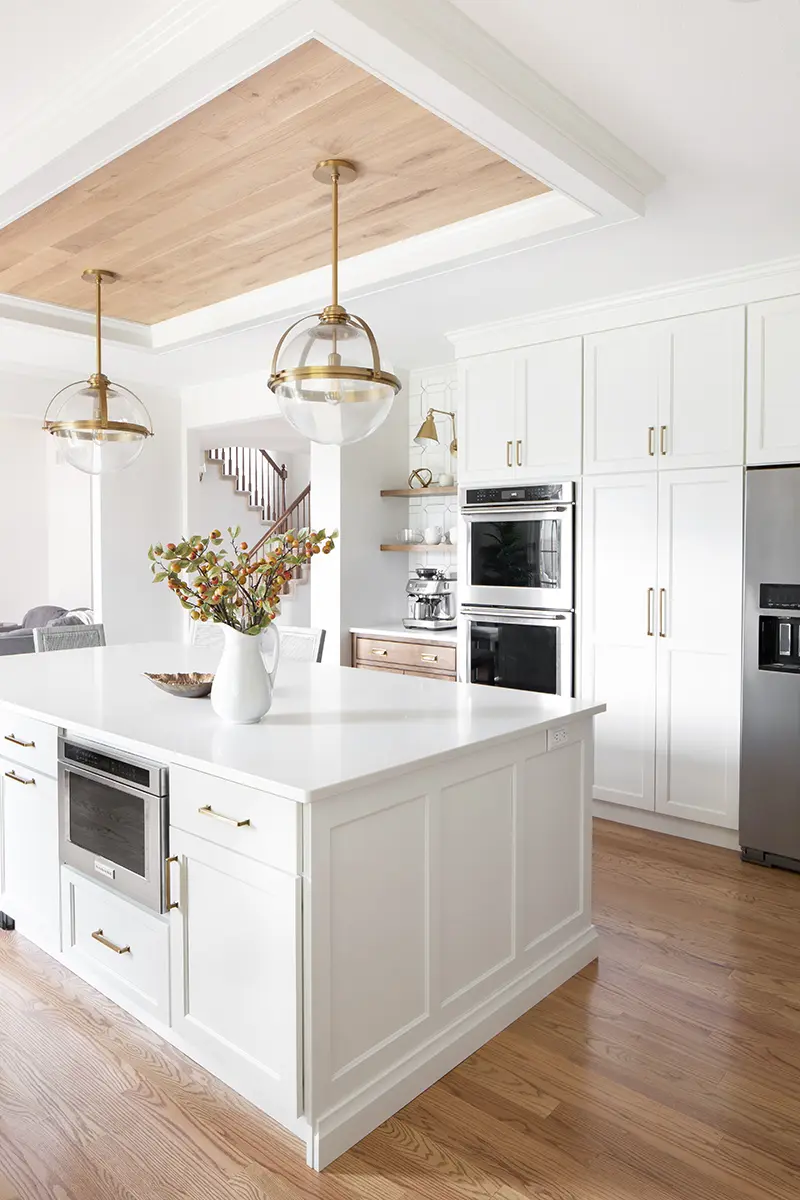 A bright white kitchen featuring wooden beams and a spacious center island, creating a warm and inviting atmosphere.