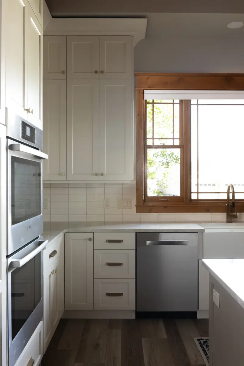 A pristine kitchen featuring white cabinets and elegant wood flooring, showcasing a bright and inviting atmosphere.