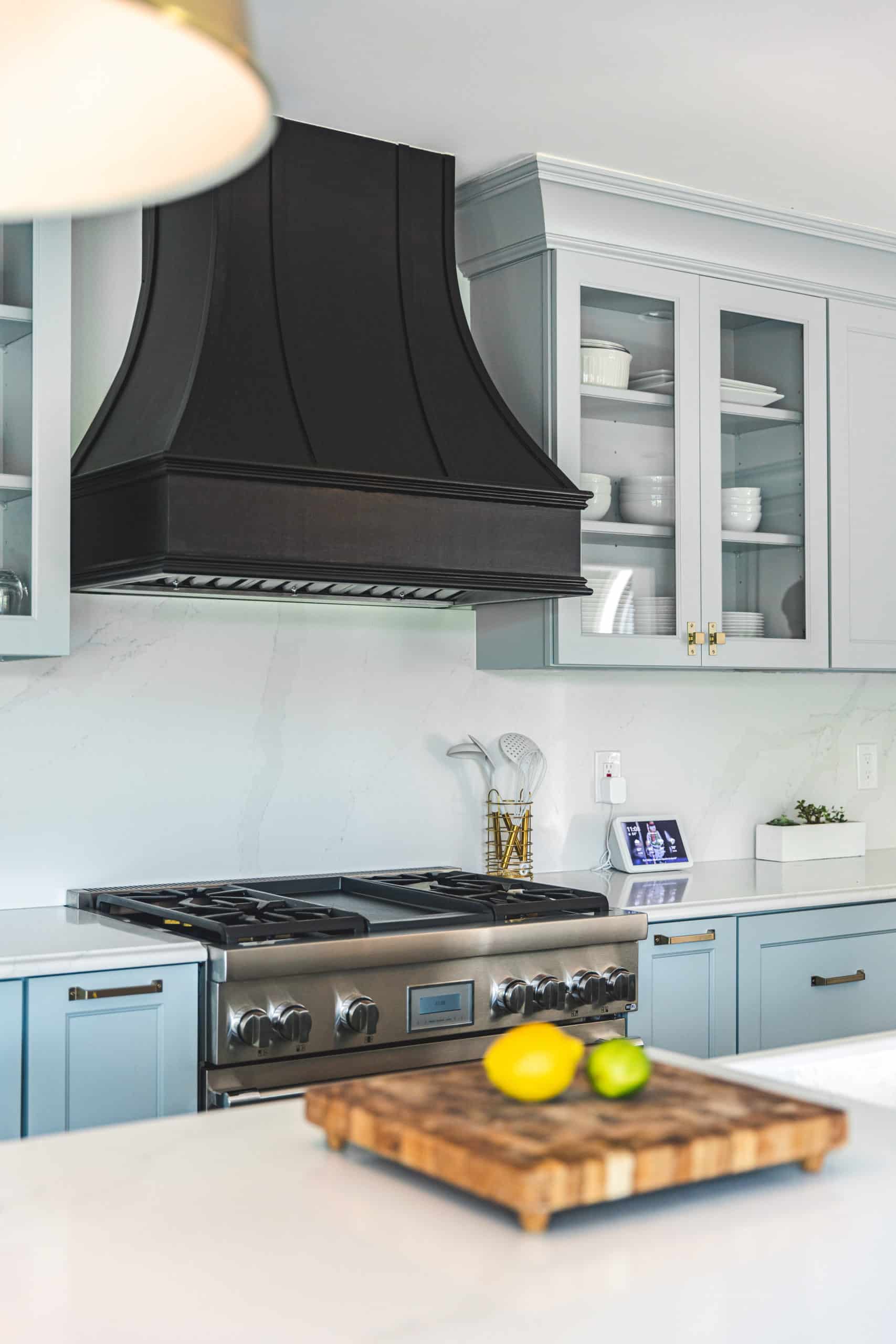 A modern kitchen featuring blue cabinets and a sleek black hood, creating a stylish and contemporary atmosphere.