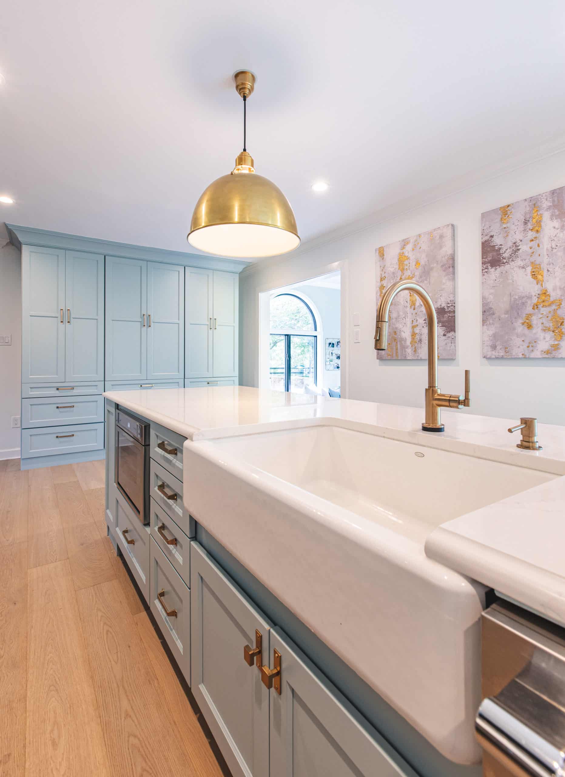 A modern kitchen featuring a sleek sink and an elegant gold pendant light hanging above.