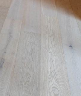 A white wooden floor showcasing the natural grain and texture of the wood, creating a bright and inviting space.