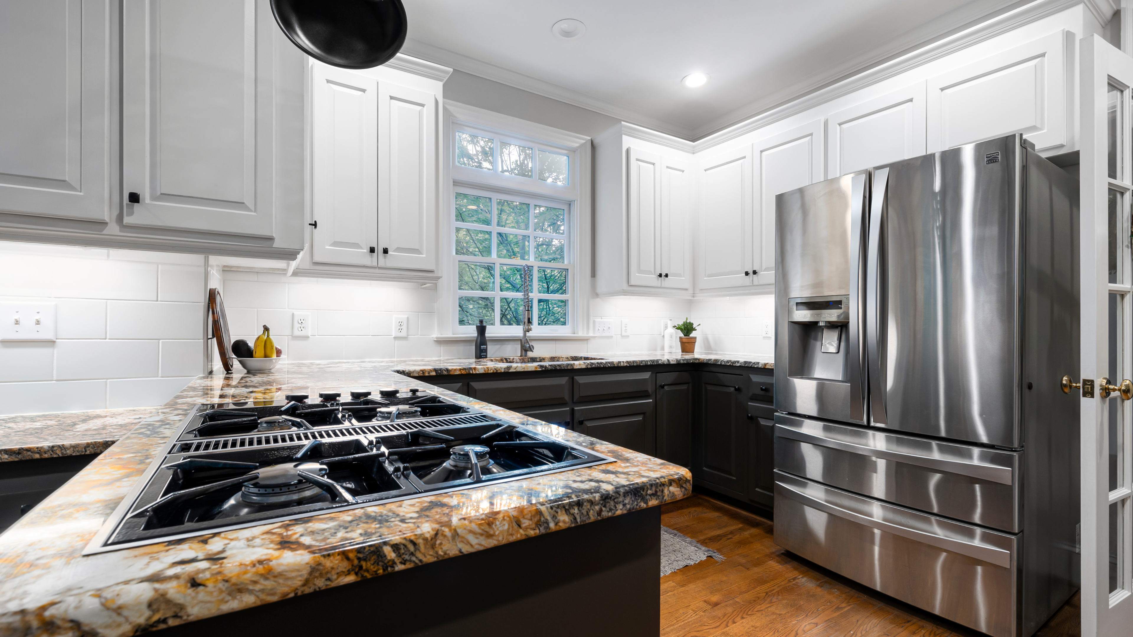 Bright kitchen with white cabinetry, a large island, and contemporary appliances, creating a welcoming cooking space.