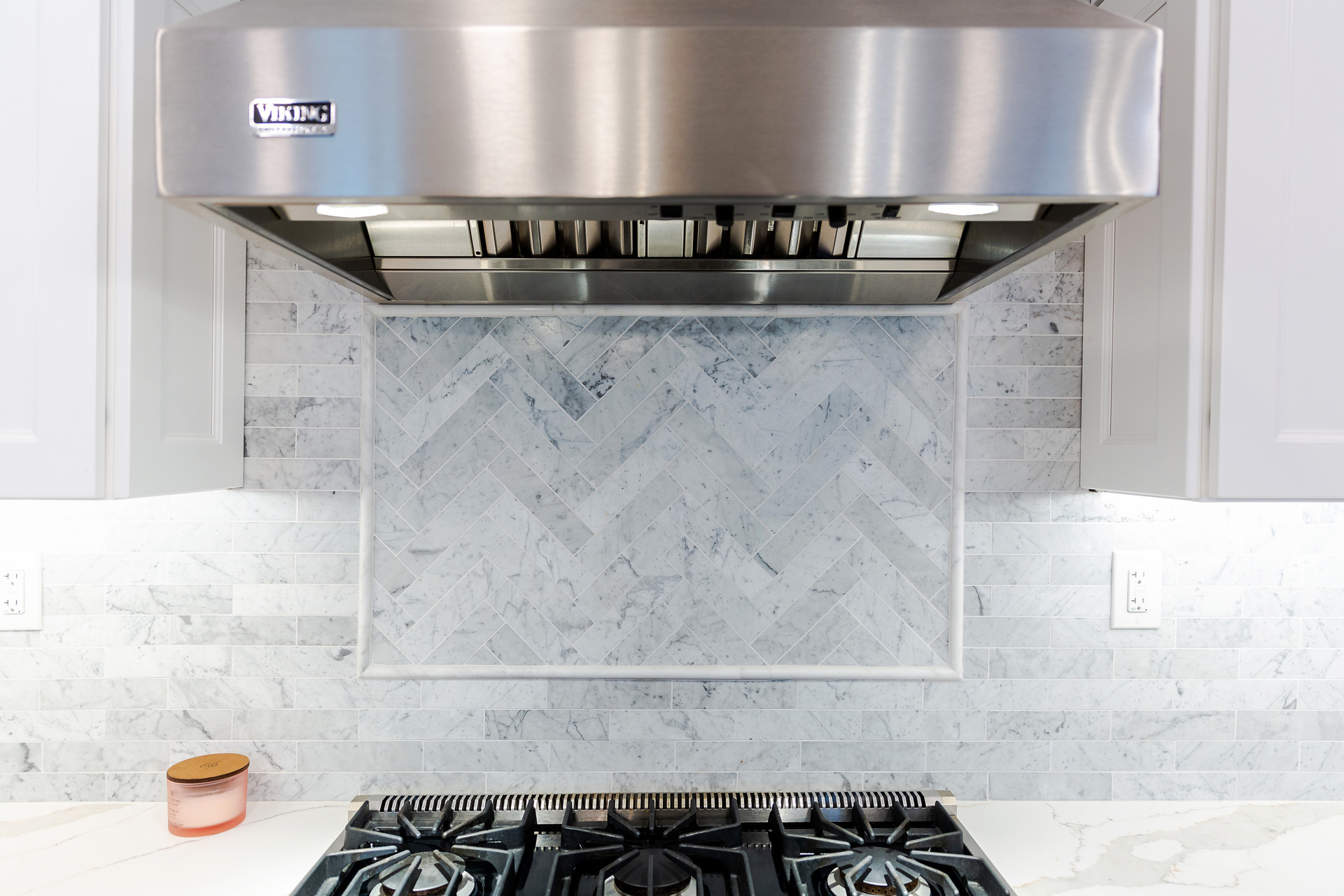 A contemporary kitchen showcasing white cabinetry and a polished stainless steel range hood, enhancing the space's elegance.