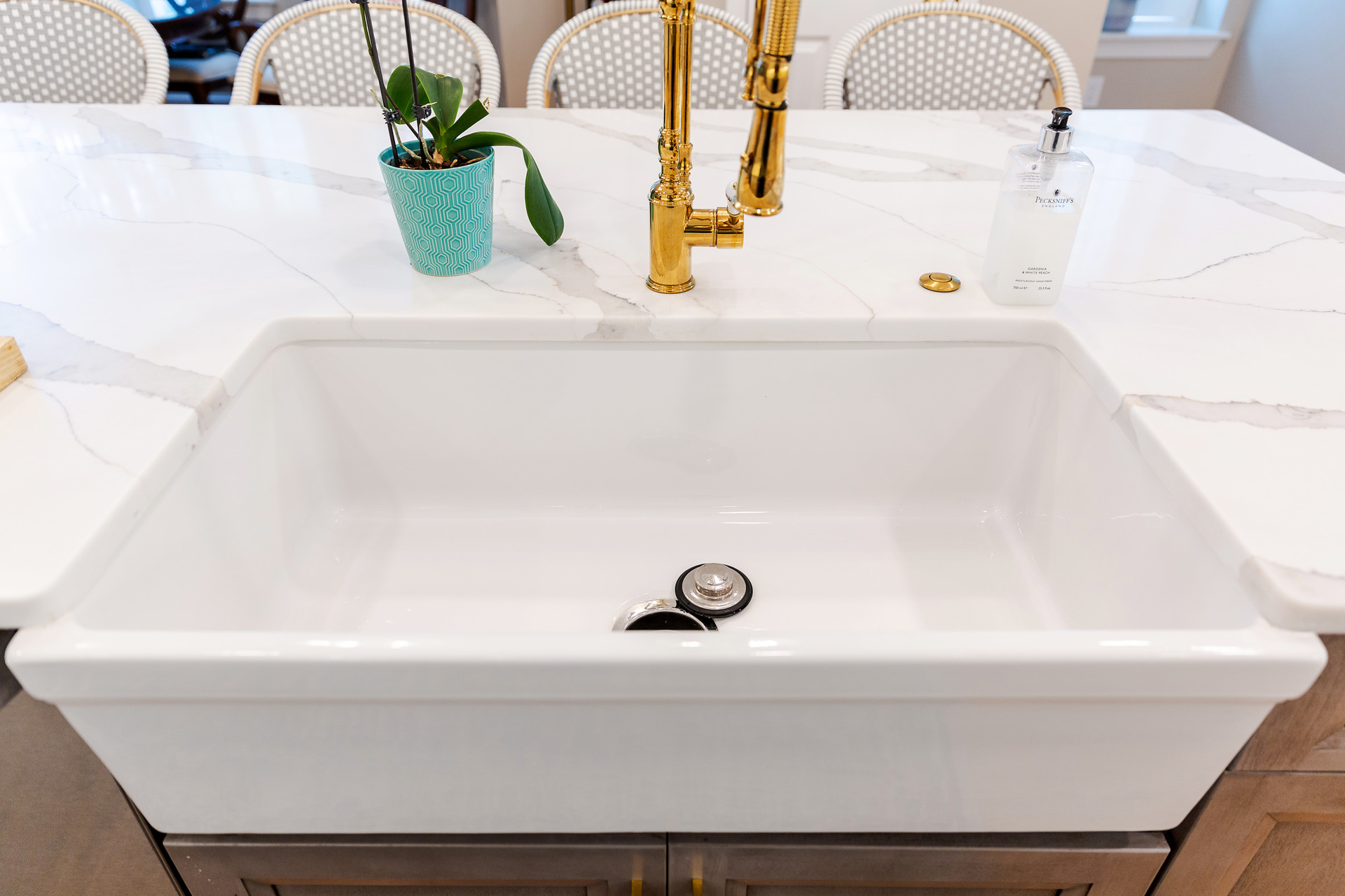 A clean white kitchen sink adorned with luxurious gold faucets, exemplifying a chic and modern kitchen design.