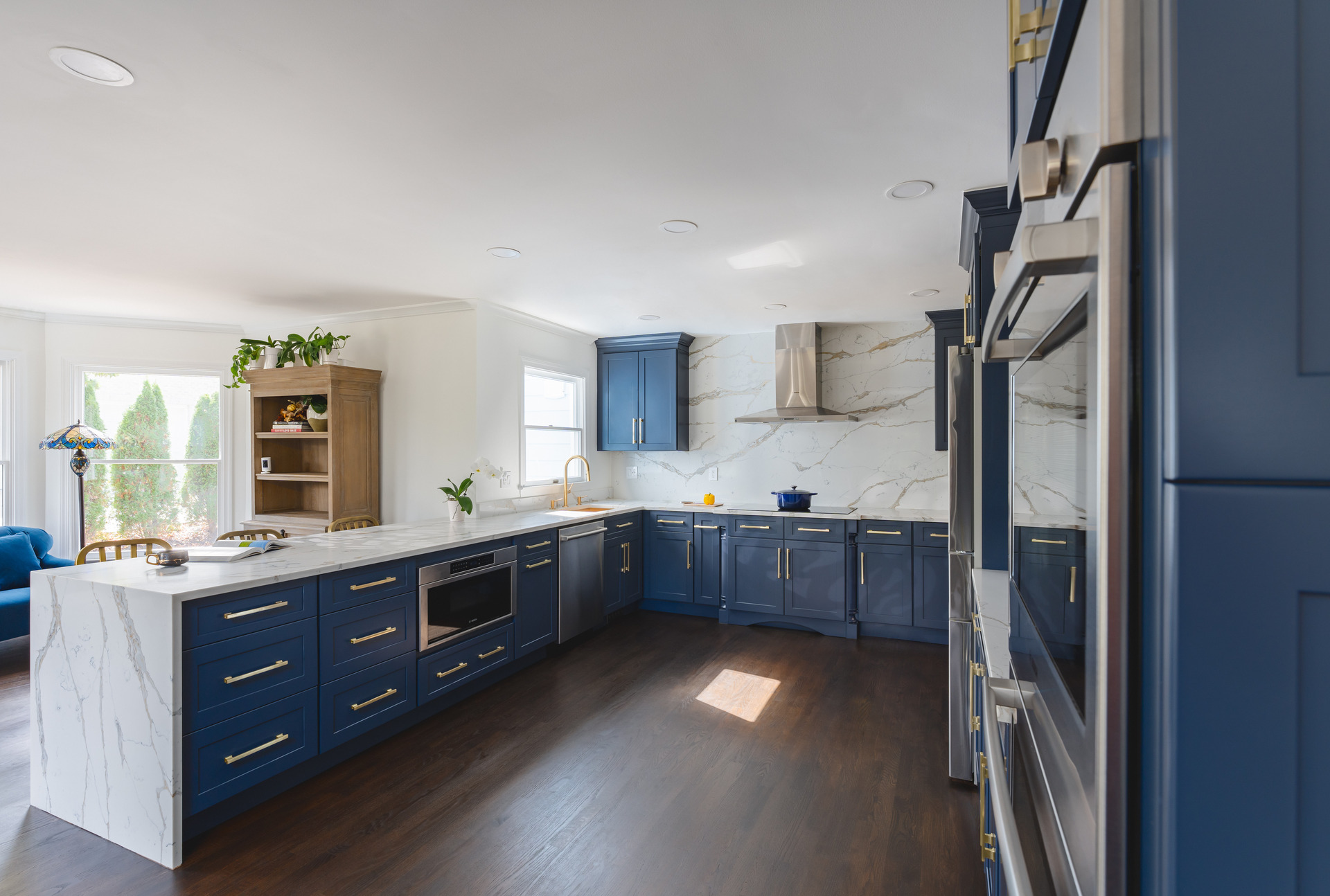 An elegant kitchen interior with blue cabinetry and a polished marble countertop, highlighting contemporary aesthetics.