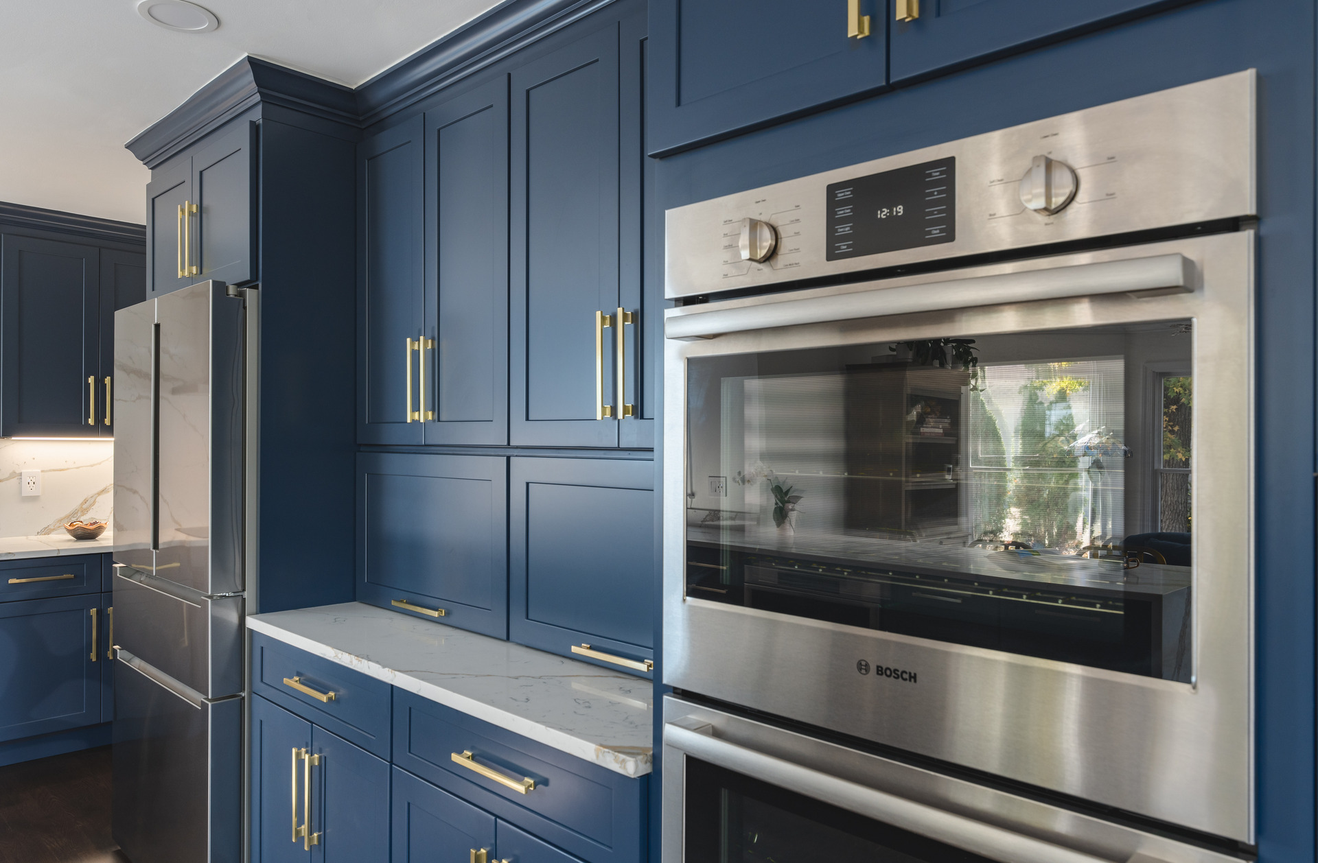 A modern kitchen featuring blue cabinets complemented by elegant gold hardware, creating a stylish and inviting atmosphere.