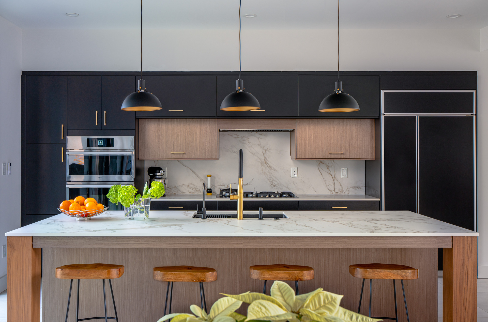 A stylish kitchen with sophisticated black cabinets complemented by a beautiful marble island.