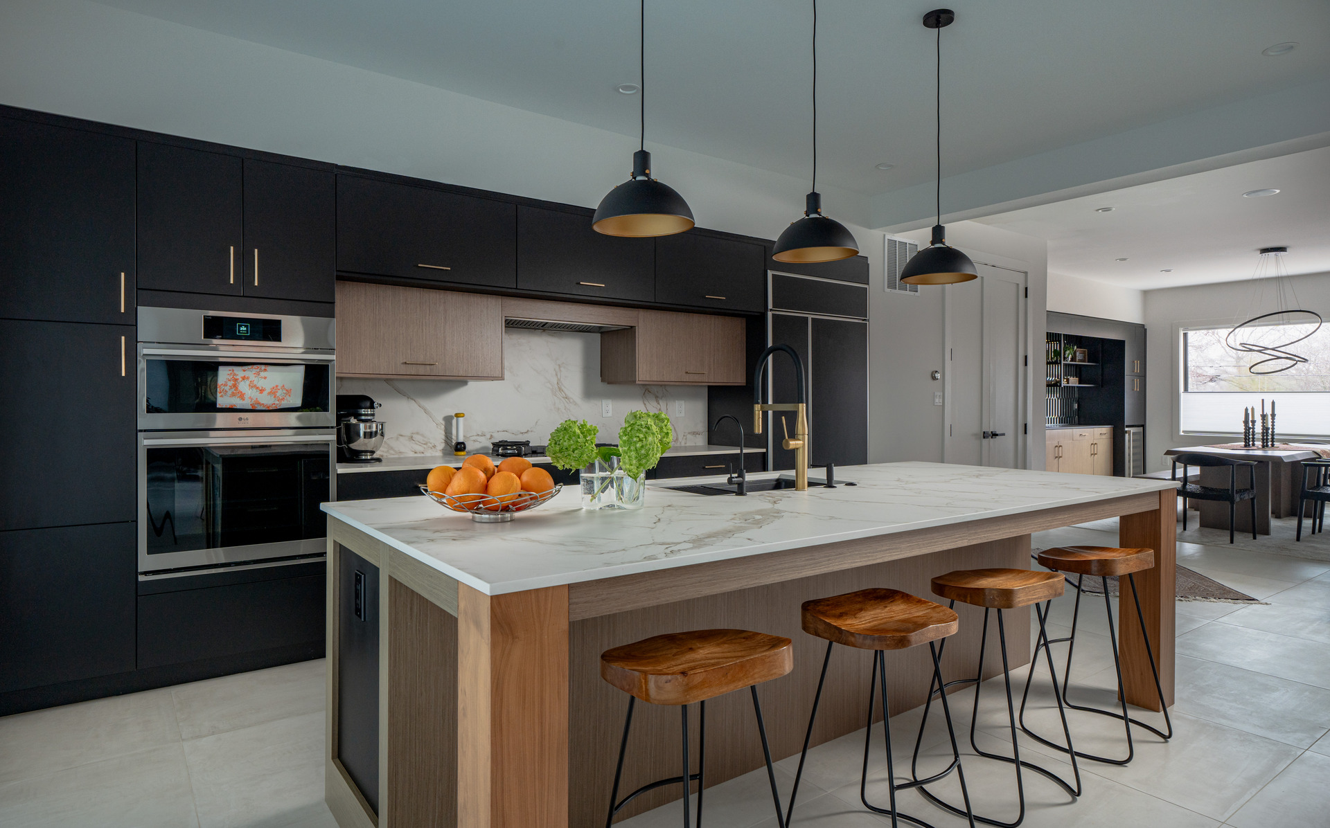 A sleek modern kitchen featuring black cabinets and a stunning marble island